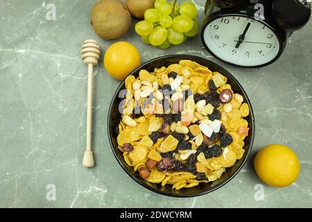 Cornflakes with milk for breakfast. Honey flakes and nuts with raisins and milk as a healthy and healthy breakfast. The clock shows six in the morning Stock Photo