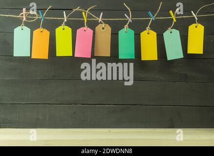 Background and nine tags in different colors. Tags and inscriptions for text. The labels are hung on a rope with multi-colored clothespins. Stock Photo