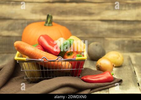 Fresh vegetables in a shopping basket. Fresh vegetables on a shopping trolley on a wooden background with place for text Stock Photo