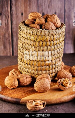 Walnuts in a wicker basket, whole and finely chopped, next to the filling and shells on a wooden background. Home storage of winter preparations Stock Photo
