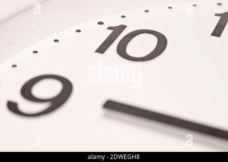 Dial of an analog clock close up. Time 08:55. White dial, black numerals. Sepia toned image. Stock Photo