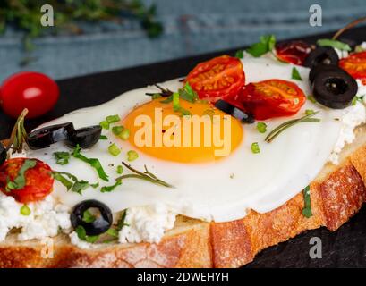 Toasted bread toast with fried eggs with yellow yolk and tomatoes, side view, close up, macro Stock Photo