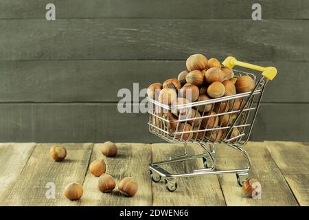 Nutritious hazelnuts in a basket and scattered on the ground. Hazelnuts in a shopping basket. Healthy and dietary orishki in the basket. Background wi Stock Photo