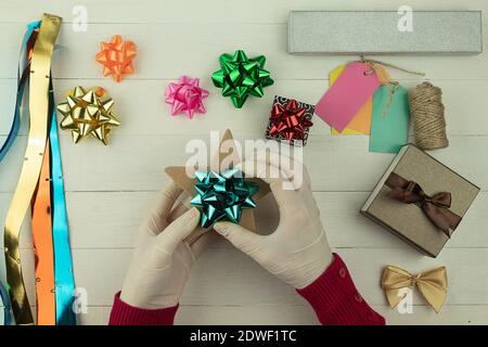 Women's hands are wrapping a Christmas present in silver wrapping paper.  Stock Photo by AllaRudenko