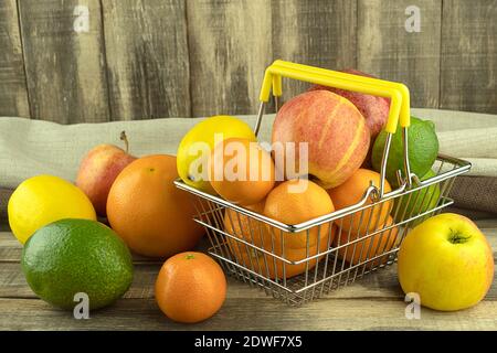 Fresh and healthy fruits in a basket on a background of wooden slats with space for text. Tangerines and oranges, grapefruit and lime, apple and avoca Stock Photo