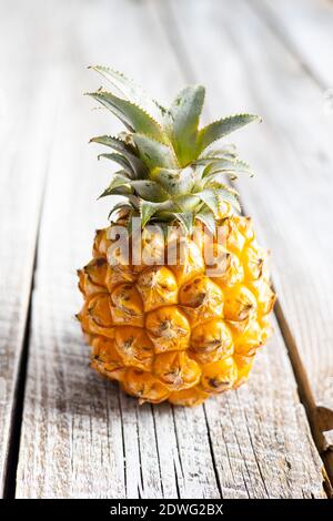 Ripe baby pineapple. Mini pineapple on wooden table. Stock Photo