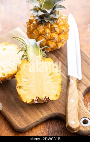 Ripe baby pineapple. Halved mini pineapple on wooden cutting board. Stock Photo