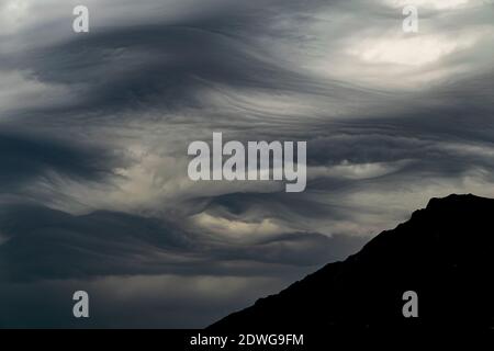 stormy weather front with thick grey clouds with a mountain silhouette Stock Photo