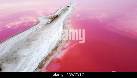 The shore of the island on the pink lake is covered with salt. Stock Photo