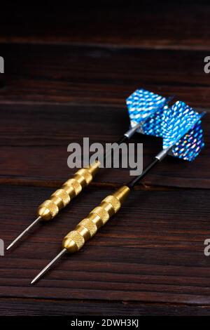 Two darts on a dark wooden table. Passion for playing darts. Stock Photo