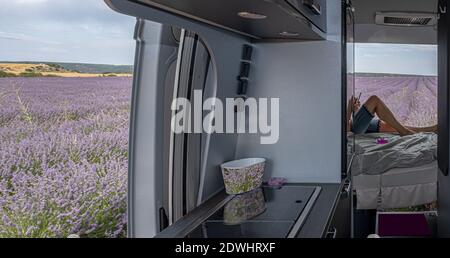 Lavender flowers in camper, mature woman using mobile Stock Photo