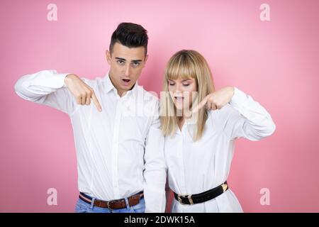 Young couple of girlfriend and boyfriend over isolated pink background looking confident with smile on face, pointing oneself with fingers proud and h Stock Photo