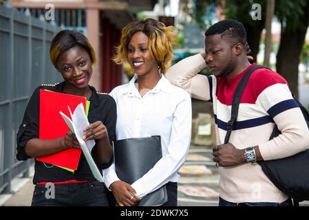 group of students standing outside after class with notebook smiling. Stock Photo