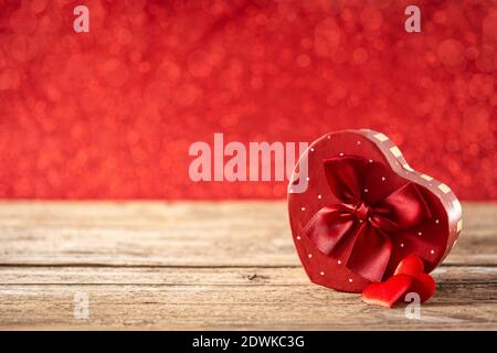Red gift box with heart shaped on wooden table and red glitter background Stock Photo