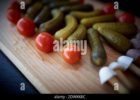Christmas tree made of pickled cucumbers, decorated with cherry tomatoes, sweet mushroom-shaped cookies below Stock Photo