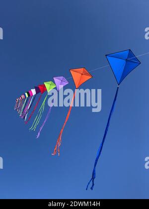 Low Angle View Of Multi Colored Kites Flying Against Clear Blue Sky