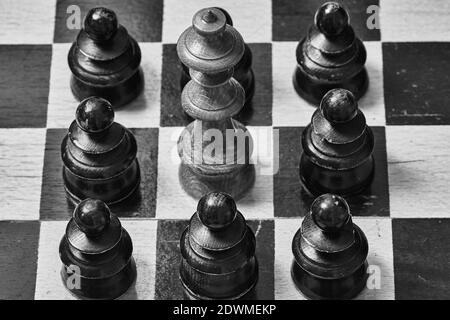 Closeup of king chess piece surrounded by black pawns Stock Photo