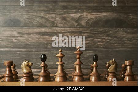 Vintage chess pieces arrangement on chessboard against wooden background Stock Photo