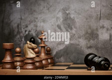 Chess pieces defeat the black king on chessboard with grey background Stock Photo