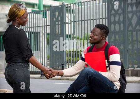 Happy friends or a couple saluting hands and looking at each other outside.Concept meeting and studying young people Stock Photo
