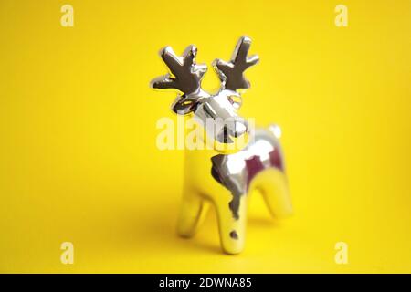 Beautiful silver reindeer toy isolated on a bright yellow background. New Year's shiny toy deer. Christmas tree toy decorations Stock Photo