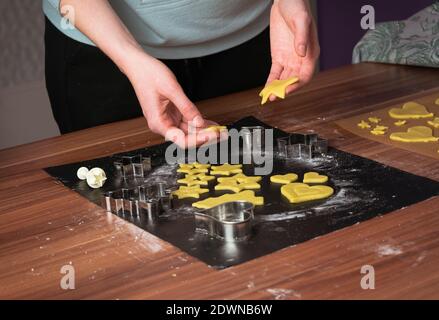 Woman making christmas cookies on black baking paper on table Stock Photo