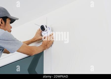 Technicians are installing a wireless cctv camera on the wall, can connect to the Internet, and control the camera via a smartphone or tablet. Stock Photo