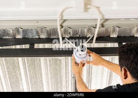 Technicians are installing a wireless cctv camera on the roof, can connect to the Internet, and control the camera via a smartphone or tablet. Stock Photo