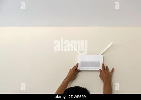 The technicians are installing a wireless internet access point connection on the wall of the room. Stock Photo