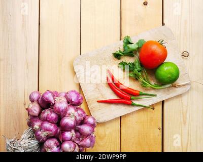 Various kinds of fresh vegetables for cooking on a wooden chopping board on a wooden floor. Stock Photo