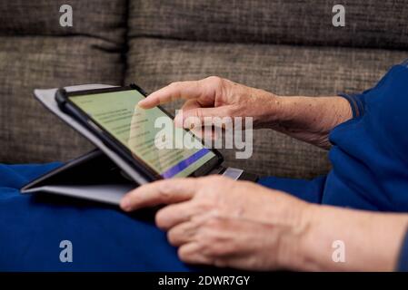 Close-up of an elderly woman's hand using a tablet. Stock Photo