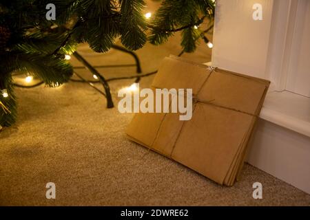 a bunch of letters to Santa Claus made of craft paper tied with a rope lie next to Christmas decorations and a Christmas tree Stock Photo