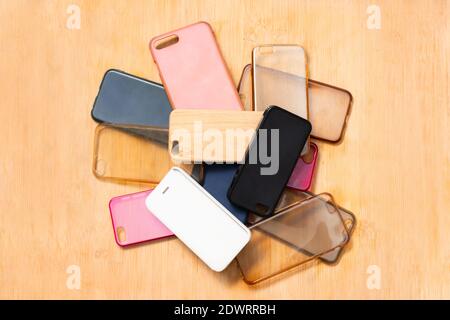 Pile of multicolored plastic back covers for mobile phones on wooden table background Stock Photo