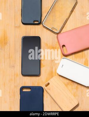 Pile of multicolored plastic back covers for mobile phones on wooden background with a phone on the side Stock Photo