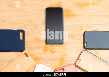 Pile of multicolored plastic back covers for mobile phones on wooden background with a phone on the side Stock Photo