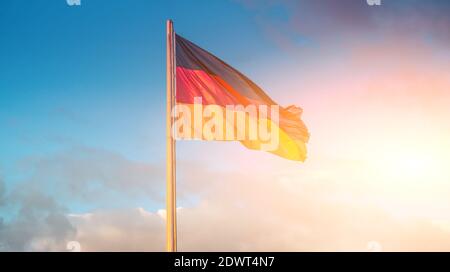 German flag waving on flagpole on blue sky background Stock Photo