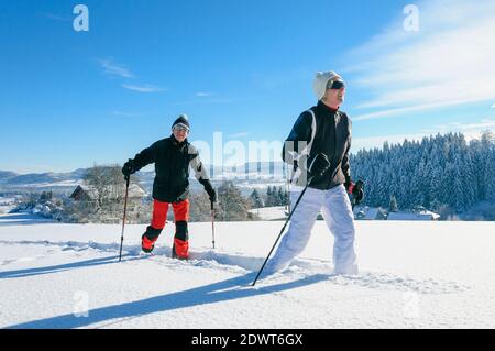 Senior couple walking in nature with snowshoes Stock Photo