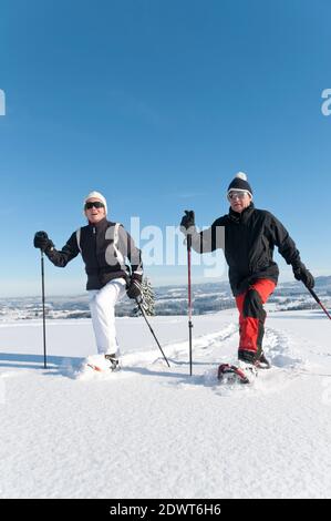 Senior couple walking in nature with snowshoes Stock Photo