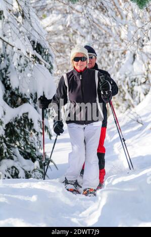 Senior couple walking in nature with snowshoes Stock Photo