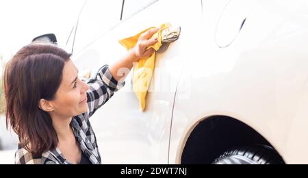 Woman polishing car door handle with microfiber rag Stock Photo