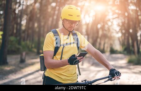 Cyclist using gps navigator on smartphone in sunny forest Stock Photo