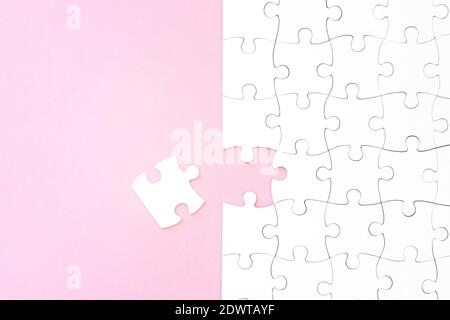 Last unconnected piece of white puzzle on pink background Stock Photo