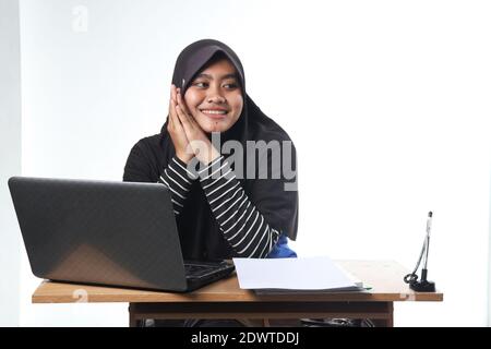 portrait of Asian woman wearing casual clothes working in an office. a veiled woman with a happy expression working at a computer. the concept of a su Stock Photo