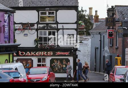 Small group of people in Carlingford village centre walking past village public house Ma Bakers in the popular County Louth coastal village Ireland. Stock Photo