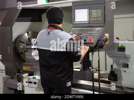 Industrial technician operating CNC lathing machine. Metalworking manufacturing factory Stock Photo