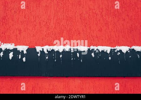 The wall texture is red with a black band covered in snow. Stock Photo