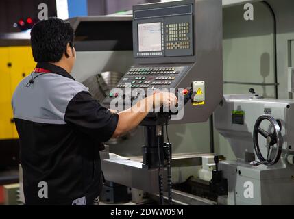 Industrial technician operating CNC lathing machine. Metalworking manufacturing factory Stock Photo