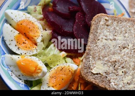 A colourful light lunch,of boiled egg, coleslaw,lettuce and beetroot with homemade wholemeal bread. Stock Photo
