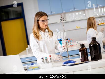 Young female researcher working with blue liquid at separatory funnel in the laboratory Stock Photo