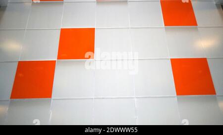 A white wall with an orange tile. Selective focus Stock Photo